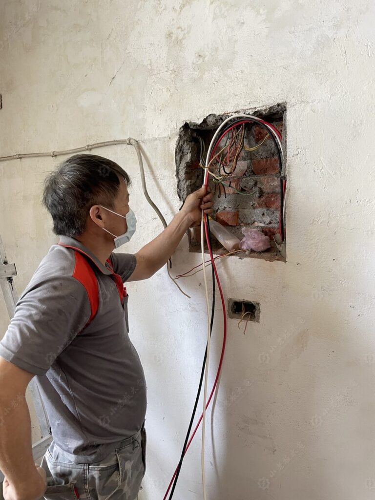 技師於牆面開孔處重新佈設電線,更換老屋舊有線路